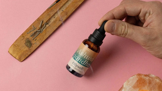 Held in hand, the Ashwagandha herbal extract from Ollywell with an incense backdrop.